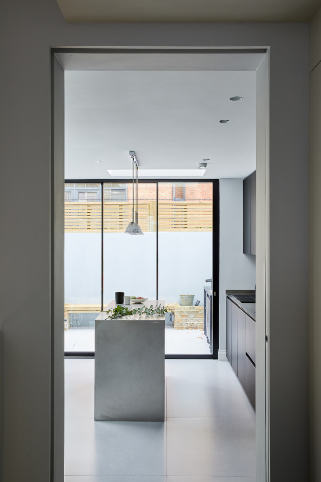 Foto på ett litet funkis linjärt kök och matrum, med släta luckor, svarta skåp, bänkskiva i rostfritt stål och en köksö