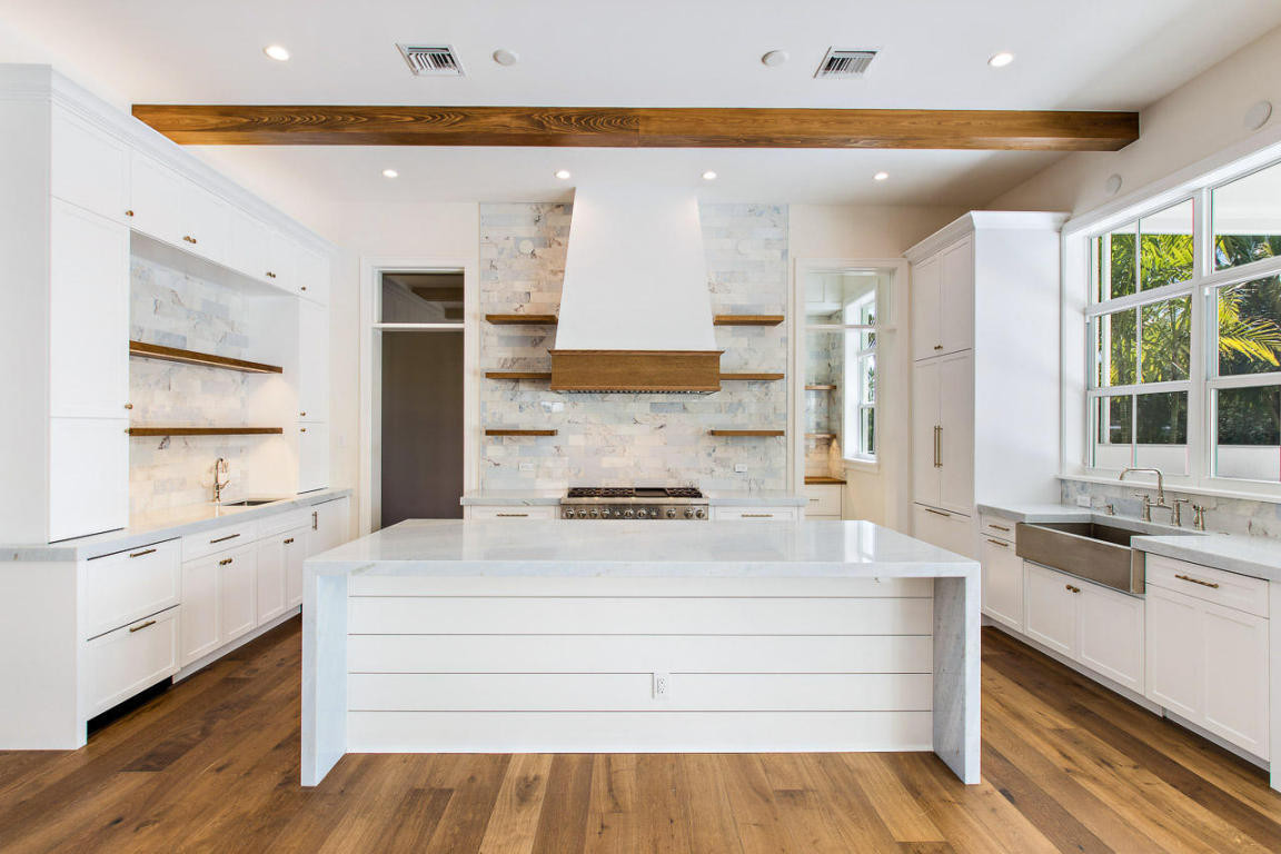 Example of a large beach style u-shaped medium tone wood floor, brown floor and exposed beam kitchen pantry design in Miami with a farmhouse sink, shaker cabinets, white cabinets, blue backsplash, mar