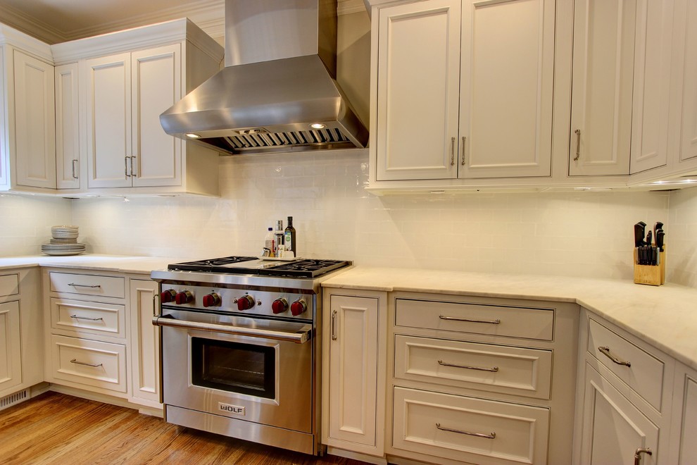 Large transitional u-shaped light wood floor kitchen pantry photo in Atlanta with an undermount sink, recessed-panel cabinets, white cabinets, quartz countertops, white backsplash, subway tile backsplash, stainless steel appliances and an island