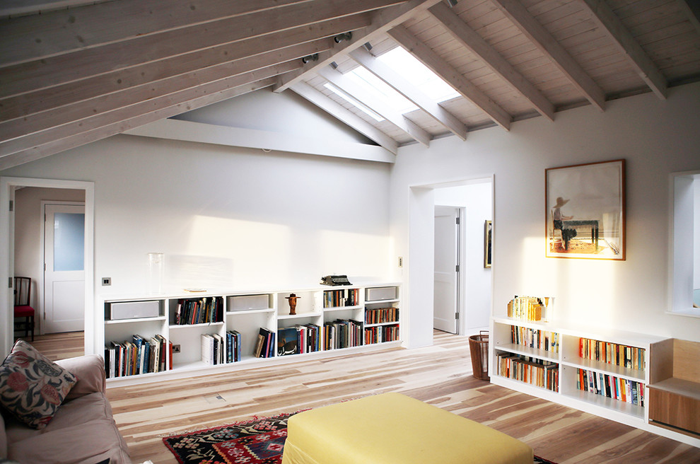 Design ideas for a mid-sized scandinavian enclosed family room in London with white walls and light hardwood floors.