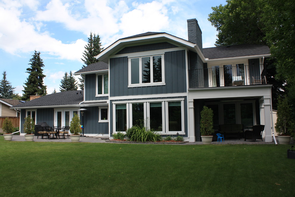 Design ideas for a large traditional two-storey blue house exterior in Calgary with concrete fiberboard siding, a clipped gable roof and a shingle roof.