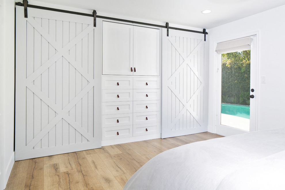 Inspiration for a mid-sized country gender-neutral built-in wardrobe in Orange County with shaker cabinets, white cabinets and light hardwood floors.