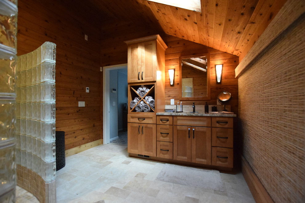 Large master bathroom in New York with recessed-panel cabinets, light wood cabinets, a curbless shower, a two-piece toilet, beige tile, travertine, brown walls, travertine floors, an undermount sink and granite benchtops.