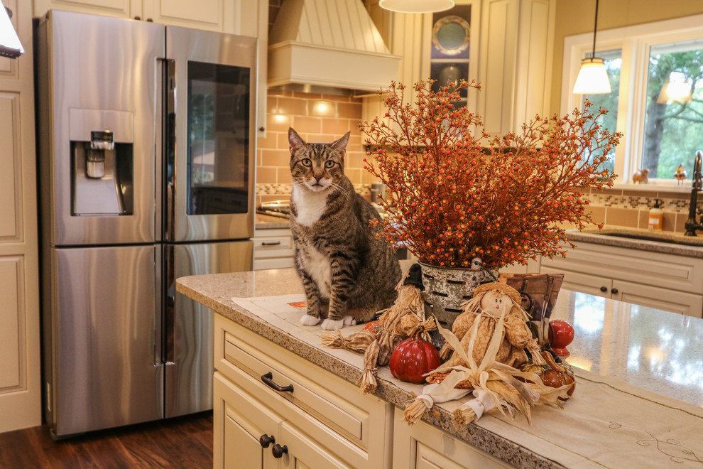 Mid-sized transitional u-shaped vinyl floor and brown floor eat-in kitchen photo with an undermount sink, raised-panel cabinets, beige cabinets, quartz countertops, brown backsplash, porcelain backsplash, stainless steel appliances and an island