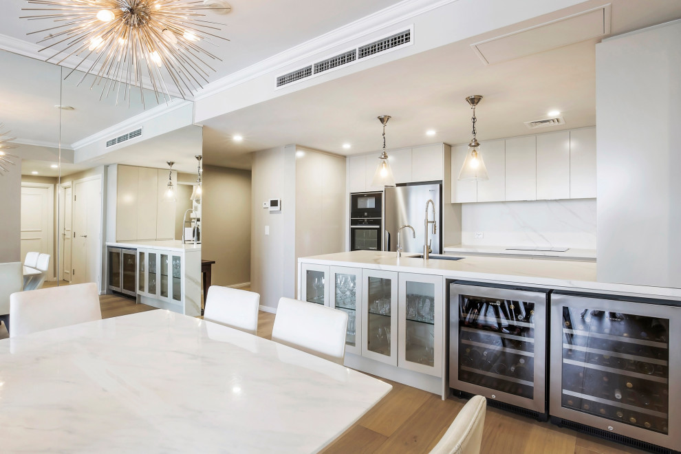 Design ideas for a mid-sized contemporary kitchen in Sydney with an undermount sink, flat-panel cabinets, beige cabinets, tile benchtops, multi-coloured splashback, porcelain splashback, stainless steel appliances, medium hardwood floors, a peninsula, brown floor and white benchtop.