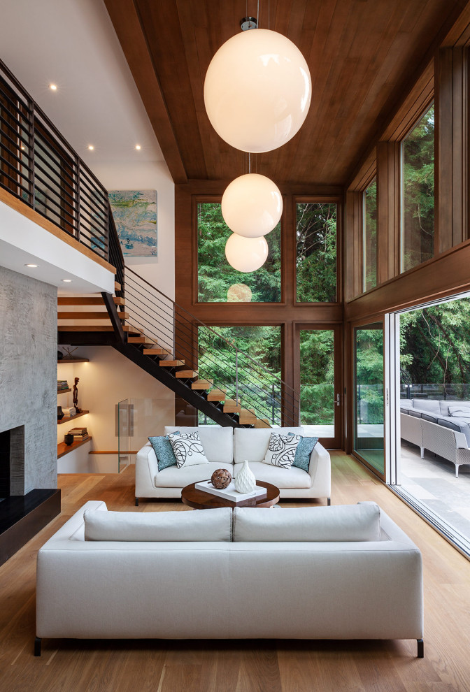 Large midcentury open concept living room in San Francisco with white walls, light hardwood floors, a standard fireplace, a concrete fireplace surround, no tv and beige floor.