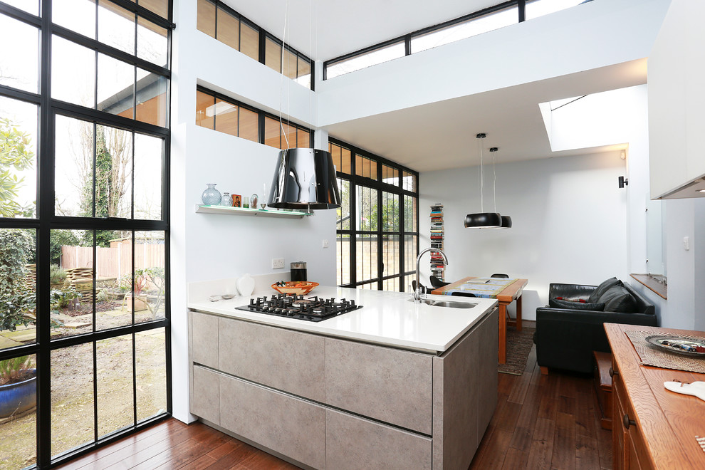 Design ideas for a contemporary eat-in kitchen in London with a peninsula, an undermount sink, flat-panel cabinets and medium hardwood floors.