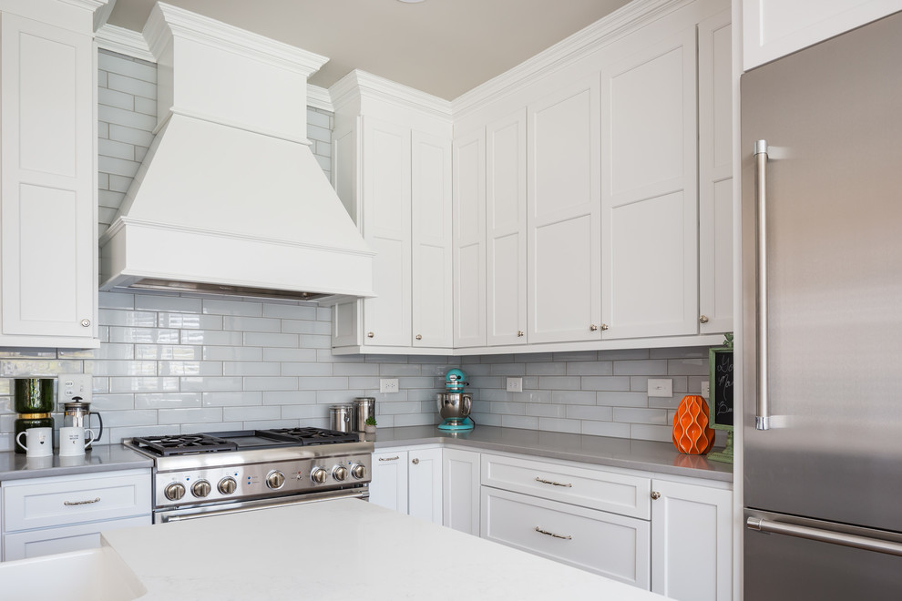 Example of a huge transitional galley medium tone wood floor open concept kitchen design in Raleigh with a farmhouse sink, flat-panel cabinets, white cabinets, quartz countertops, gray backsplash, ceramic backsplash, stainless steel appliances and two islands