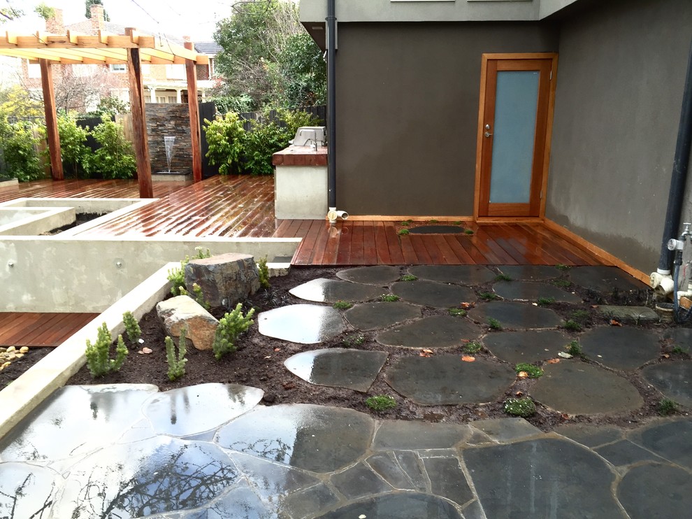 Large contemporary backyard formal garden in Melbourne with a water feature.