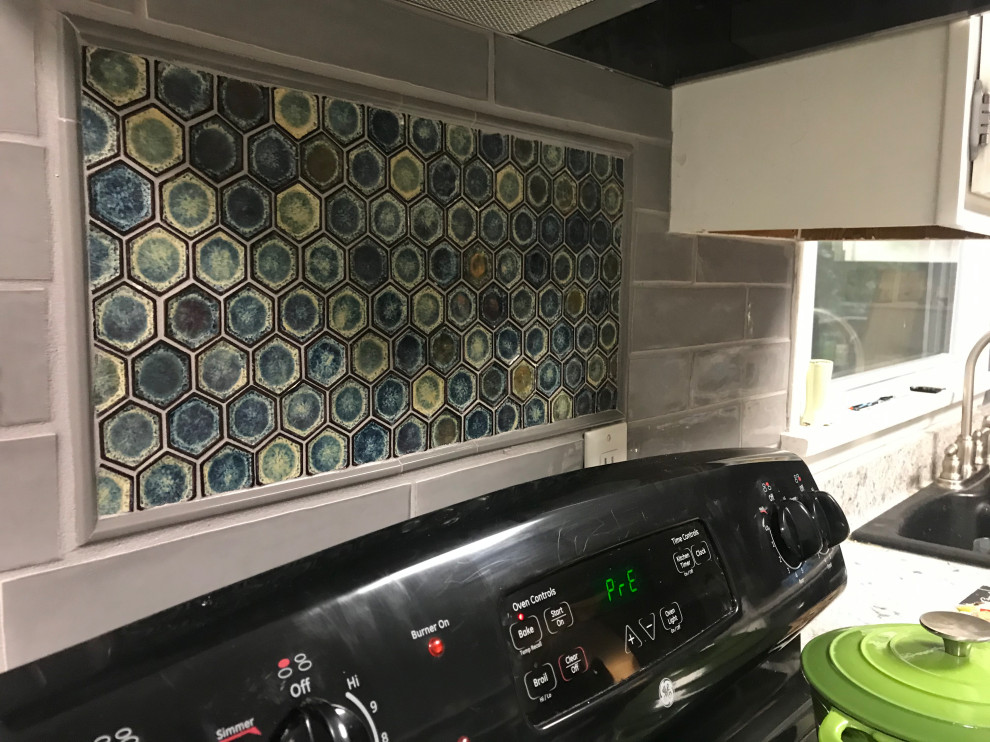 Inspiration for a transitional kitchen remodel with shaker cabinets, white cabinets, granite countertops, gray backsplash, ceramic backsplash and black appliances