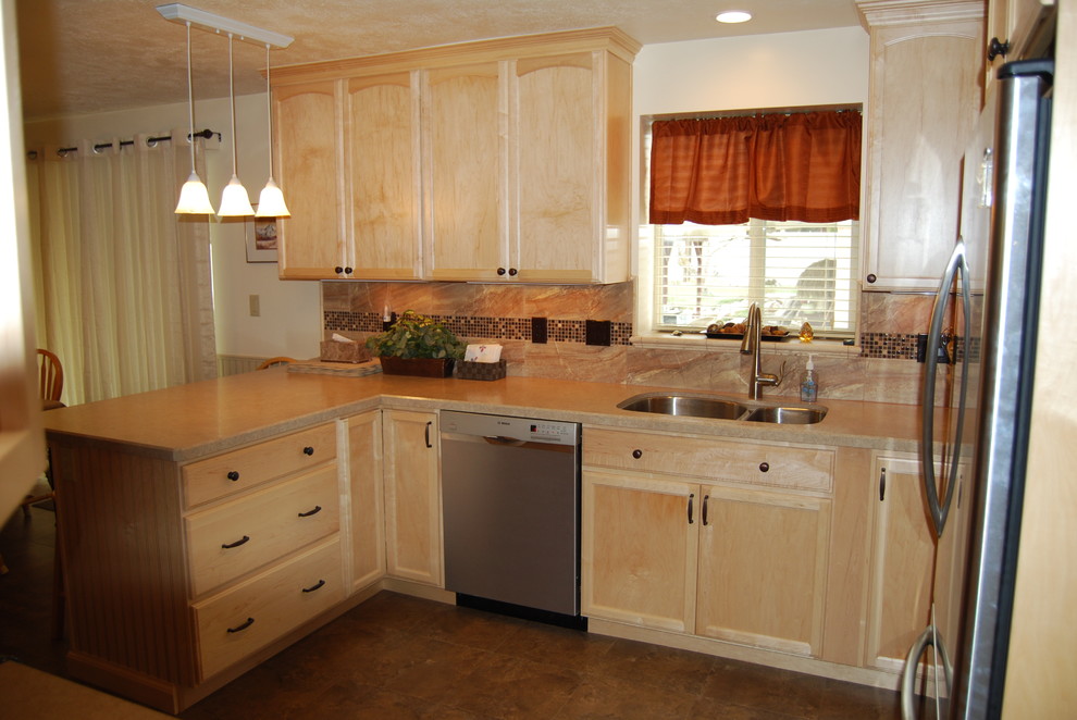 Photo of a traditional u-shaped eat-in kitchen in Salt Lake City with a double-bowl sink, flat-panel cabinets, light wood cabinets, laminate benchtops, brown splashback, mosaic tile splashback, stainless steel appliances, a peninsula and porcelain floors.