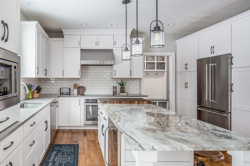 Example of a large transitional l-shaped eat-in kitchen design with a drop-in sink, recessed-panel cabinets, white cabinets, quartzite countertops, white backsplash, stainless steel appliances and an island
