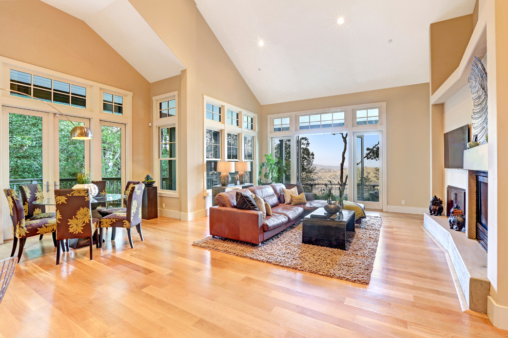 Photo of a large traditional open concept living room in San Francisco with beige walls, light hardwood floors, a standard fireplace and a wall-mounted tv.