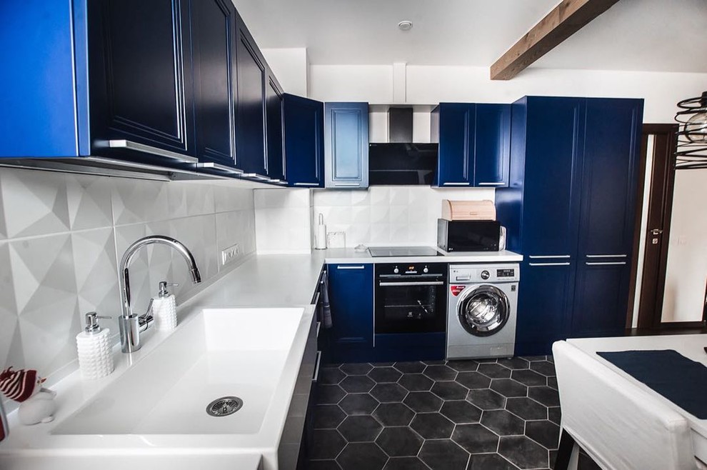 This is an example of a mid-sized contemporary l-shaped eat-in kitchen in Other with a drop-in sink, blue cabinets, solid surface benchtops, white splashback, ceramic splashback, black appliances, ceramic floors, no island, recessed-panel cabinets, black floor and white benchtop.