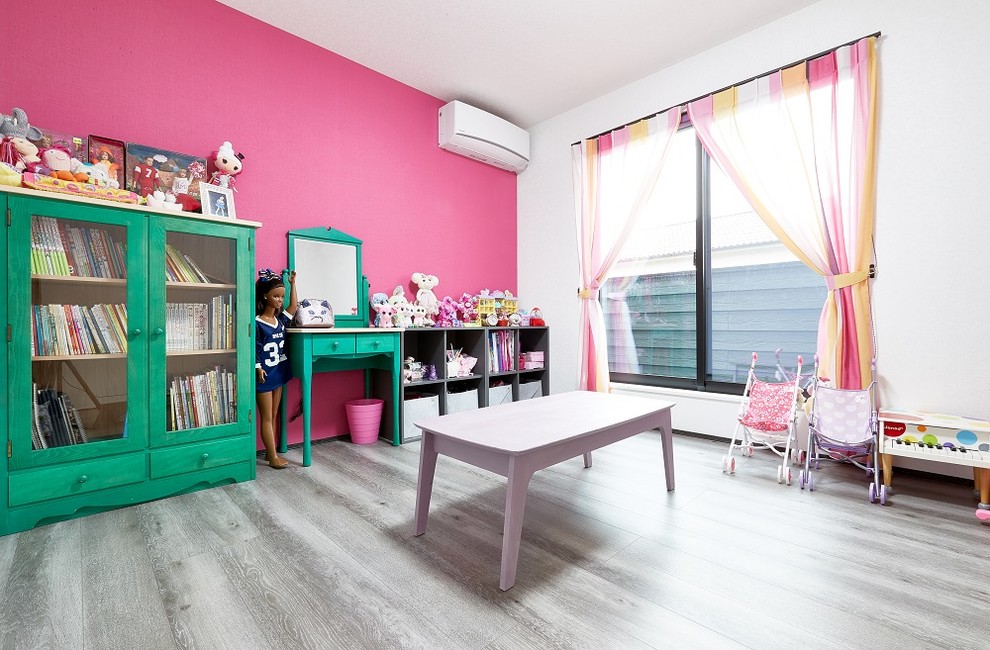 This is an example of a kids' room for girls in Osaka with pink walls, plywood floors and brown floor.
