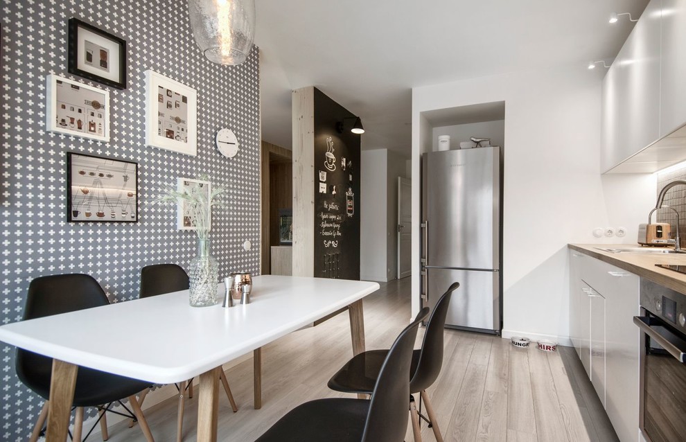 Inspiration for a mid-sized scandinavian single-wall eat-in kitchen in Saint Petersburg with a drop-in sink, flat-panel cabinets, white cabinets, wood benchtops, ceramic splashback, stainless steel appliances, laminate floors and no island.