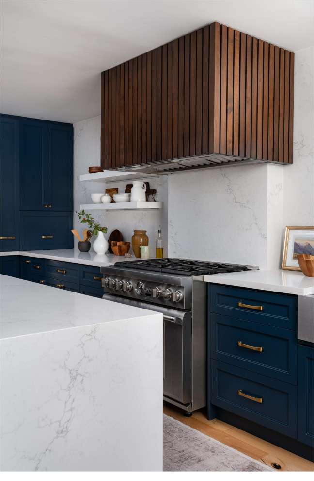 Inspiration for a mid-sized transitional l-shaped medium tone wood floor and beige floor eat-in kitchen remodel in Toronto with a farmhouse sink, shaker cabinets, blue cabinets, quartz countertops, white backsplash, quartz backsplash, stainless steel appliances, an island and white countertops