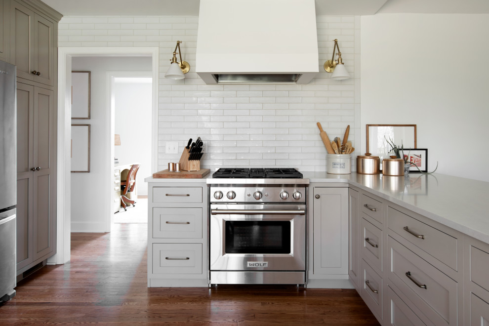 Idéer för ett stort klassiskt vit kök, med en undermonterad diskho, luckor med profilerade fronter, beige skåp, bänkskiva i kvarts, vitt stänkskydd, stänkskydd i tunnelbanekakel, rostfria vitvaror, mellanmörkt trägolv, en halv köksö och brunt golv