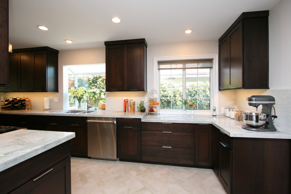 Mid-sized transitional l-shaped porcelain tile kitchen photo in Orange County with a double-bowl sink, recessed-panel cabinets, dark wood cabinets, quartzite countertops, white backsplash, glass tile backsplash, stainless steel appliances and no island
