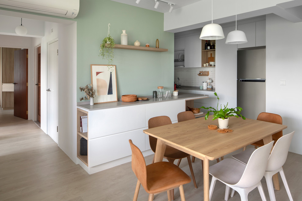 Scandinavian kitchen/dining combo in Singapore with green walls, light hardwood floors and beige floor.