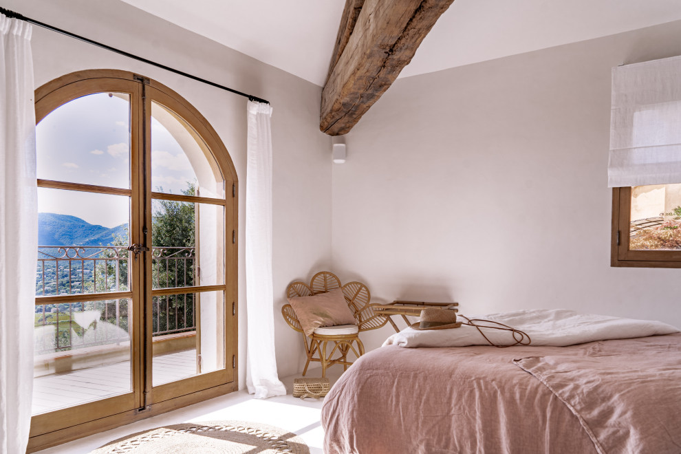 Ejemplo de dormitorio infantil mediterráneo grande con paredes blancas, suelo de cemento, suelo beige y vigas vistas