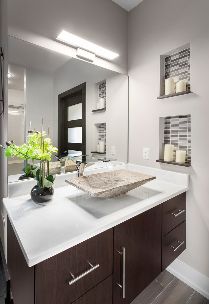 This is an example of a mid-sized modern master bathroom in Detroit with flat-panel cabinets, dark wood cabinets, a freestanding tub, a corner shower, a one-piece toilet, white tile, subway tile, beige walls, ceramic floors, a vessel sink and engineered quartz benchtops.