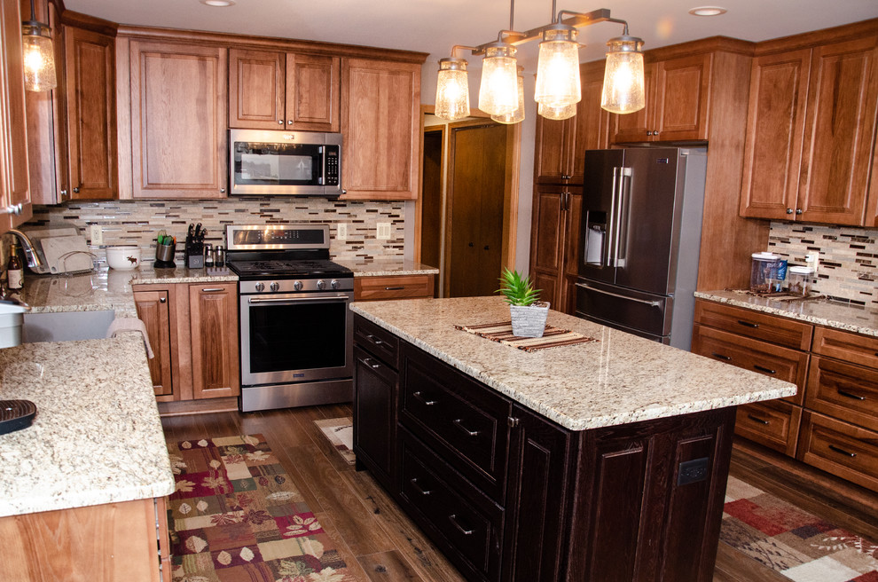 Photo of a mid-sized transitional u-shaped eat-in kitchen in Detroit with an undermount sink, medium wood cabinets, granite benchtops, multi-coloured splashback, mosaic tile splashback, stainless steel appliances, laminate floors, with island and beige benchtop.