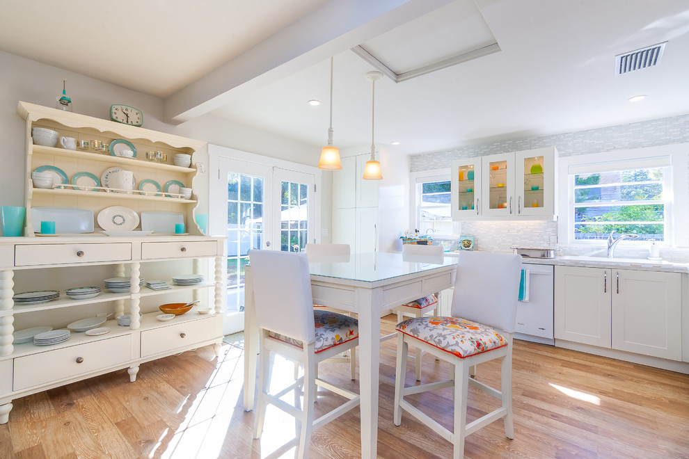 This is an example of a small traditional kitchen in Tampa with a single-bowl sink, shaker cabinets, white cabinets, tile benchtops, multi-coloured splashback, glass sheet splashback, white appliances and light hardwood floors.