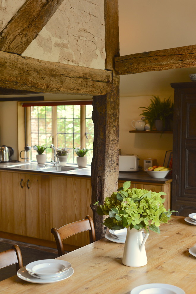 Design ideas for a mid-sized country eat-in kitchen in Sussex with a double-bowl sink, flat-panel cabinets, light wood cabinets, granite benchtops, brick floors, with island and black benchtop.
