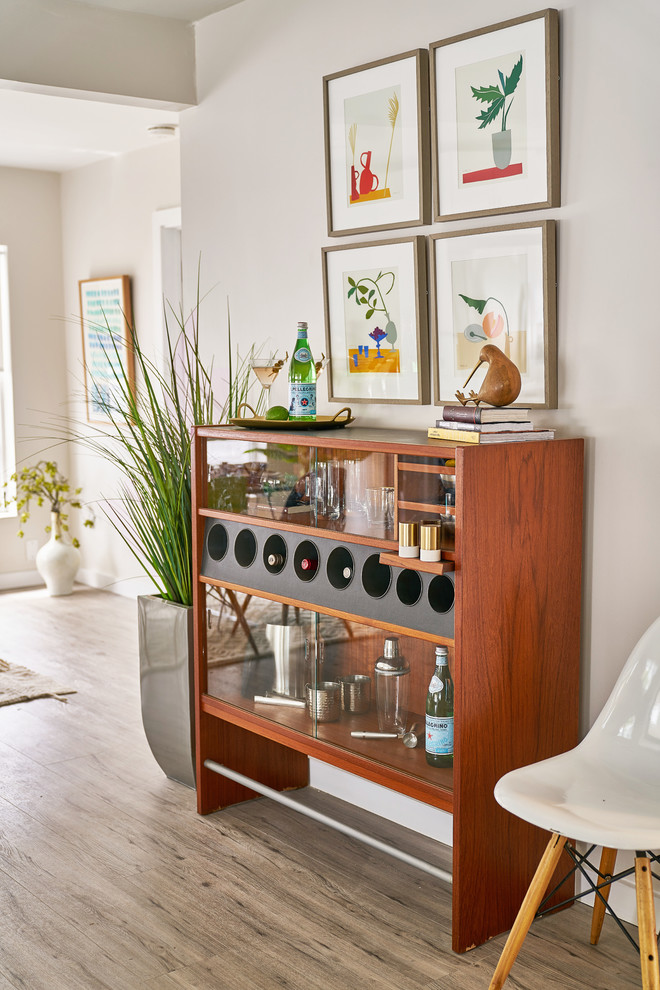 Design ideas for a small midcentury single-wall wet bar in Tampa with no sink, glass-front cabinets, medium wood cabinets, wood benchtops, light hardwood floors, beige floor and brown benchtop.