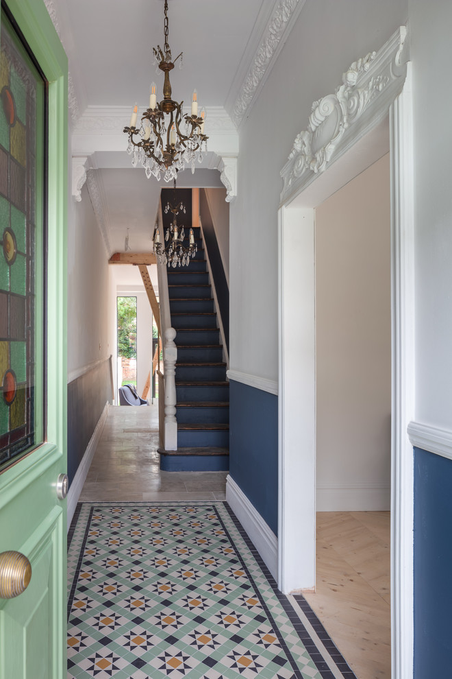 Photo of an eclectic entry hall in Manchester with a single front door, a green front door, multi-coloured walls and multi-coloured floor.