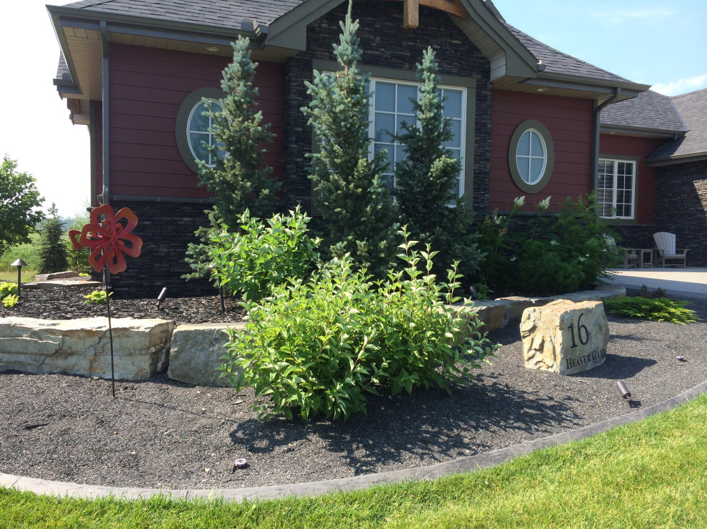This is an example of a large traditional front yard garden in Calgary with with flowerbed and natural stone pavers.