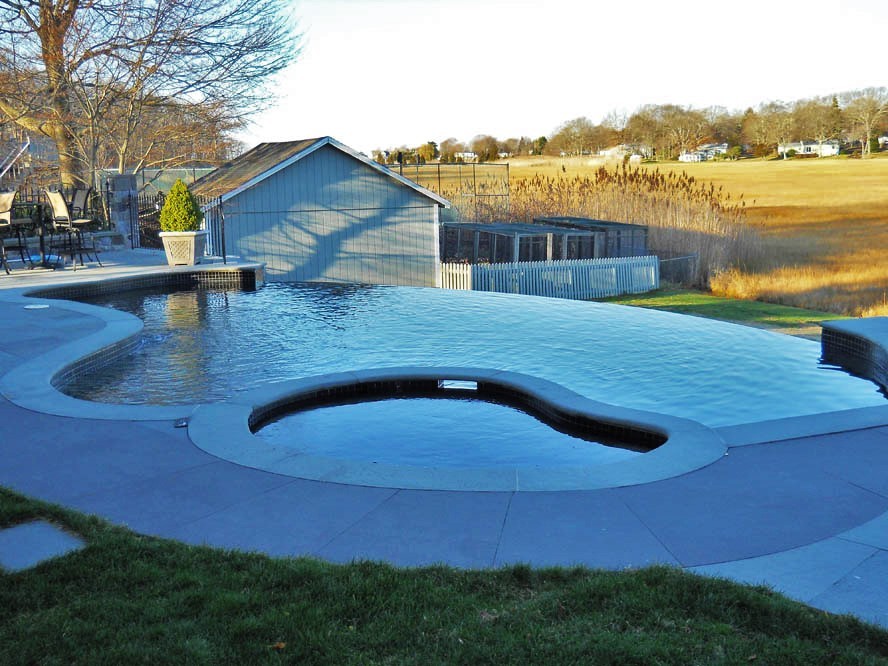 Inspiration for a large modern backyard custom-shaped infinity pool in New York with a hot tub and stamped concrete.