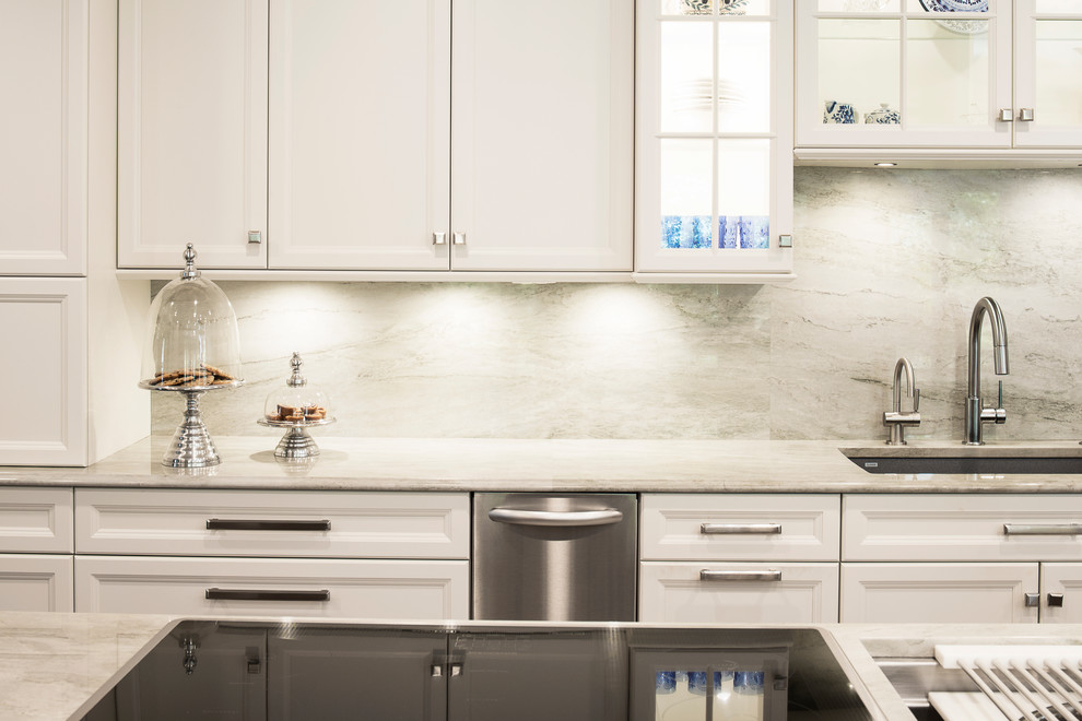 Inspiration for a large transitional single-wall medium tone wood floor and brown floor kitchen remodel in Denver with an undermount sink, recessed-panel cabinets, white cabinets, white backsplash, stone slab backsplash, stainless steel appliances and an island