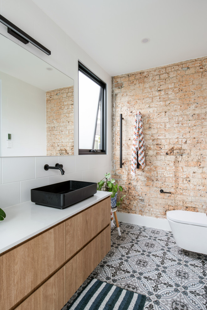 Modernes Badezimmer mit flächenbündigen Schrankfronten, hellbraunen Holzschränken, beiger Wandfarbe, Aufsatzwaschbecken, grauem Boden, weißer Waschtischplatte, Doppelwaschbecken, schwebendem Waschtisch und Ziegelwänden in Sydney