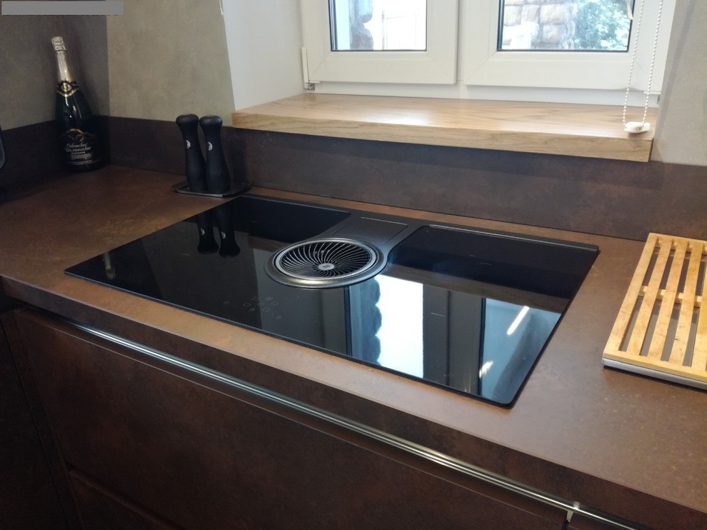 This is an example of a large industrial u-shaped eat-in kitchen in Saint Petersburg with an undermount sink, flat-panel cabinets, brown cabinets, black appliances, porcelain floors, a peninsula, brown floor and brown benchtop.