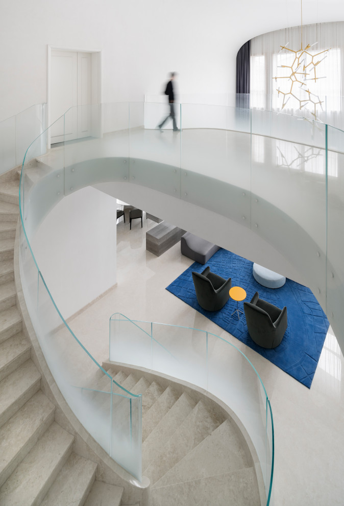 This is an example of an expansive contemporary curved glass railing staircase in Other with marble treads and marble risers.