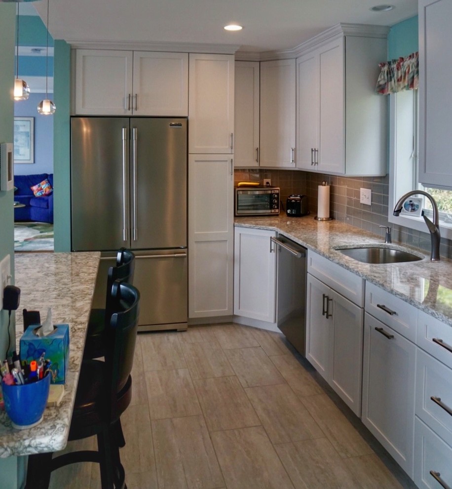 Small transitional galley porcelain tile and gray floor eat-in kitchen photo in Boston with a single-bowl sink, shaker cabinets, white cabinets, quartz countertops, gray backsplash, glass tile backsplash, stainless steel appliances and a peninsula