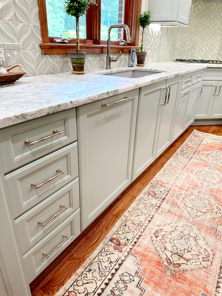 Eat-in kitchen - transitional l-shaped medium tone wood floor eat-in kitchen idea with shaker cabinets, green cabinets, quartzite countertops, porcelain backsplash, paneled appliances and an island