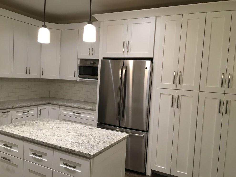 Large transitional u-shaped dark wood floor and brown floor kitchen photo in Chicago with an undermount sink, shaker cabinets, white cabinets, granite countertops, white backsplash, subway tile backsplash, stainless steel appliances and an island