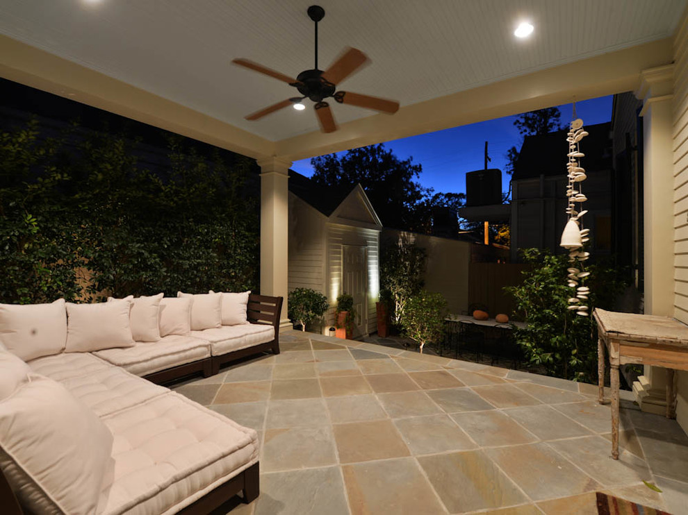 Photo of a mid-sized traditional backyard verandah in New Orleans with natural stone pavers and a roof extension.