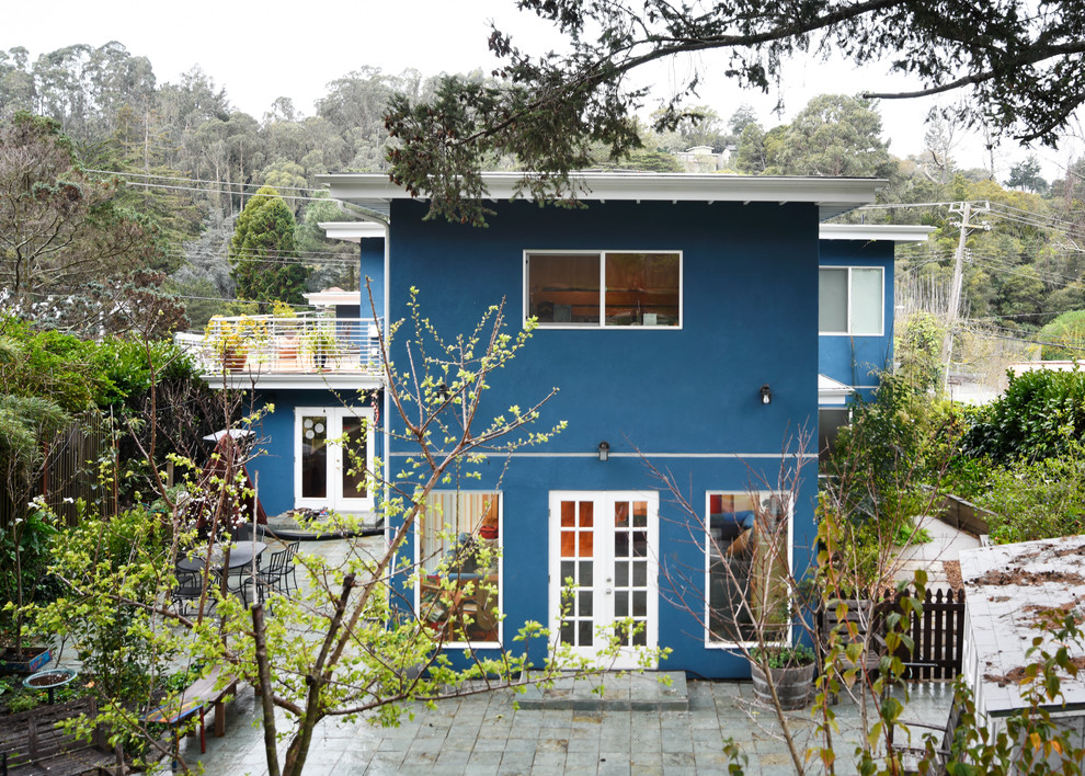 Mid-sized modern blue two-story stucco flat roof idea in San Francisco with a mixed material roof