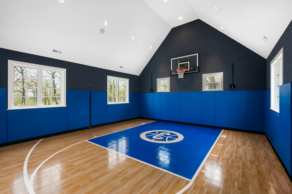 Large transitional indoor sport court in Chicago with light hardwood floors and black walls.