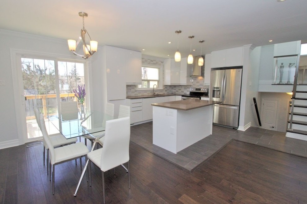 Inspiration for a mid-sized transitional l-shaped porcelain tile and brown floor open concept kitchen remodel in Toronto with an undermount sink, flat-panel cabinets, white cabinets, wood countertops, multicolored backsplash, glass tile backsplash, stainless steel appliances and an island