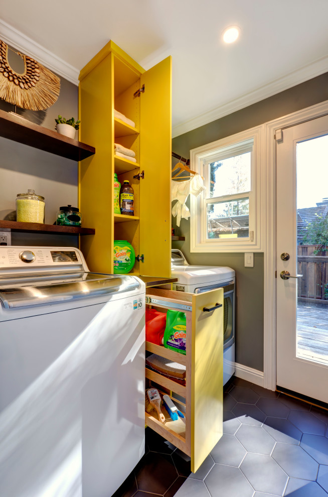 Inspiration for a small eclectic utility room in San Francisco with flat-panel cabinets, yellow cabinets, wood worktops, grey walls, porcelain flooring, a side by side washer and dryer and black floors.