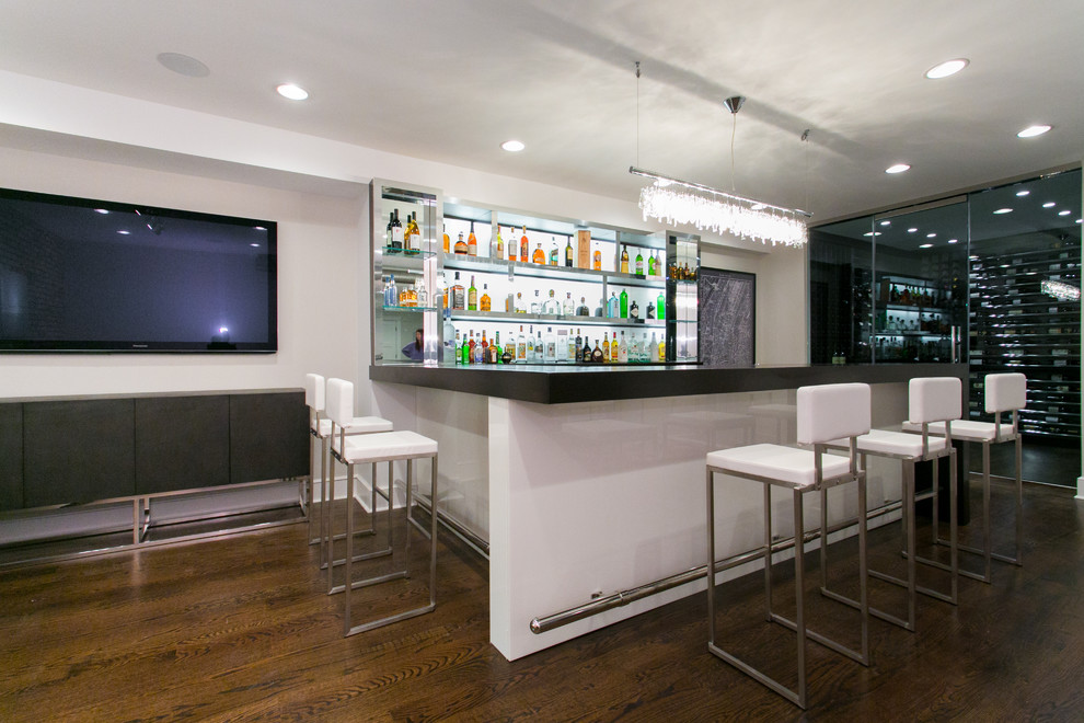 Photo of a large contemporary u-shaped seated home bar in New York with dark hardwood floors, glass benchtops, white splashback, brown floor, black benchtop and open cabinets.