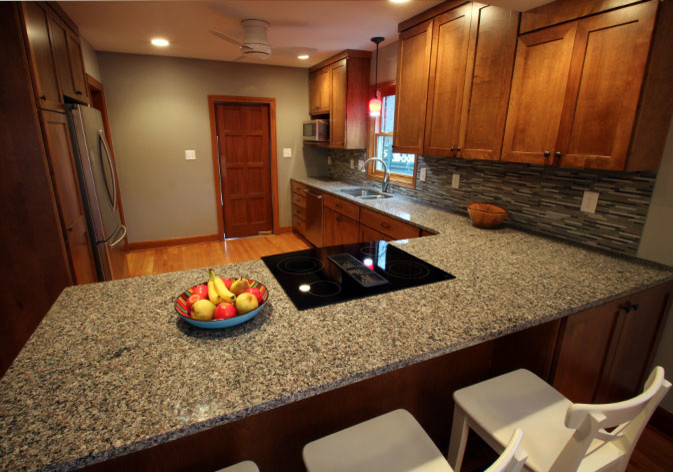 Inspiration for a mid-sized transitional l-shaped light wood floor eat-in kitchen remodel with an undermount sink, shaker cabinets, dark wood cabinets, granite countertops, multicolored backsplash, mosaic tile backsplash, stainless steel appliances and a peninsula