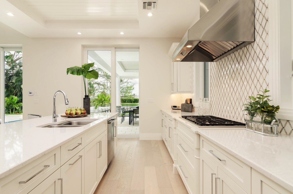 Modern single-wall eat-in kitchen in Miami with a drop-in sink, shaker cabinets, white cabinets, quartzite benchtops, yellow splashback, ceramic splashback, stainless steel appliances, with island and white benchtop.