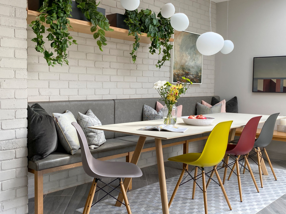 Idée de décoration pour une grande salle à manger design avec un mur blanc, un sol gris et un mur en parement de brique.