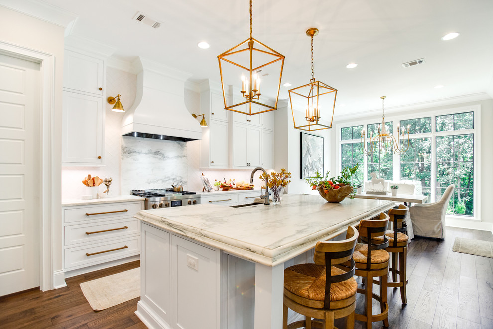 Photo of a country galley eat-in kitchen in Birmingham with recessed-panel cabinets, white cabinets, white splashback, medium hardwood floors, with island, brown floor and white benchtop.